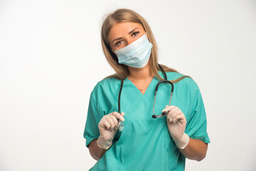 Blonde female doctor wearing face mask and putting stethoscope to her neck