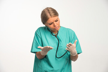 Blonde female doctor in blue uniform with stethoscope in the neck looking to her hands