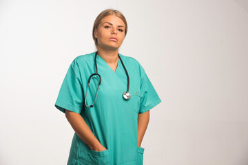 Blonde female doctor in blue uniform with stethoscope in the neck looks confident