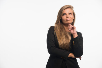 Young businesswoman in black suit looking up and thinking