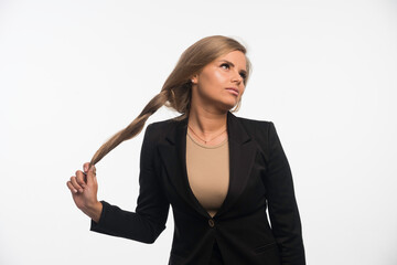 Obraz premium Young businesswoman in black suit playing with her hair and looks seductive