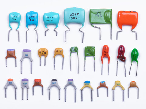 Set of small capacitors. Different type in different colors. Colorful small ceramic, metal, film capacitors. Green, blue, orange, red capacitors. On white background. Top view.