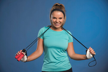 Young sportive woman hanging jumping ropes from her neck and smiling
