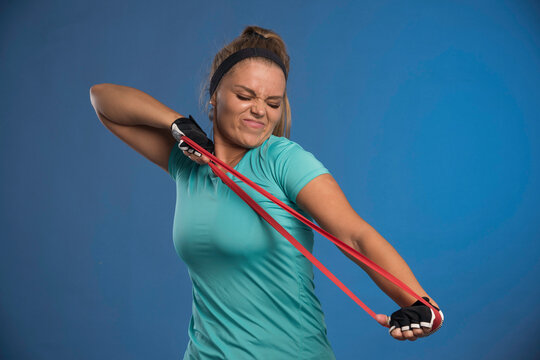 Young sportive woman stretching her arm muscles and looks strengthless