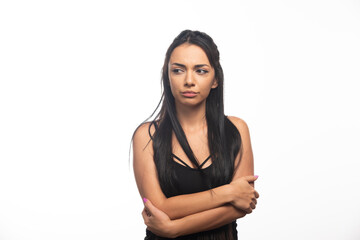 Portrait of young woman posing with crossed arms on white background
