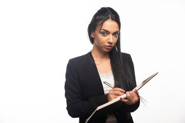 Portrait of young businesswoman writing in notebook with pen