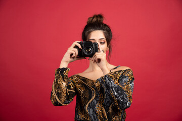 Brunette girl holding a professional dslr camera and doing photosession