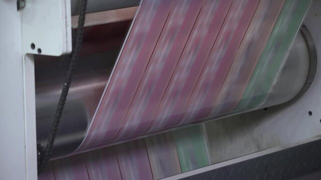 Printing house. Flexo printing. Film spins between shafts. Roller machine prints. Anilox.
