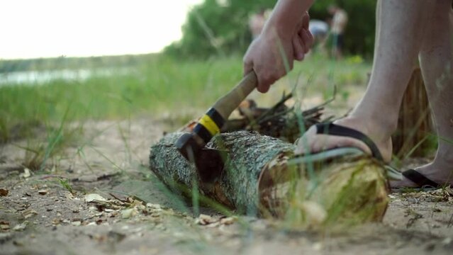 man chopping log for fire with an ax for chopping wood. Tourist camping in forest. High quality FullHD footage