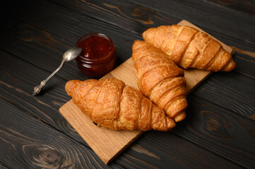 Tasty and delicious croissants with jam on a wooden table