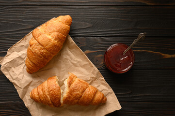 Tasty and delicious croissants with jam on a wooden table