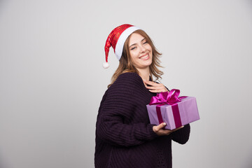 Young woman in Santa hat holding a gift box present