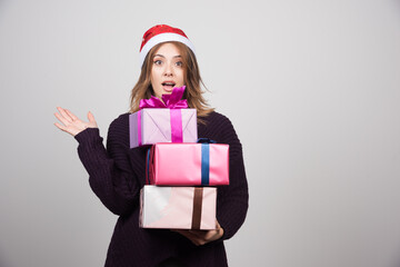 Young woman with Santa hat holding gift boxes presents