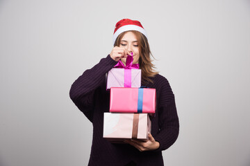 Fototapeta na wymiar Young woman with Santa hat holding gift boxes presents