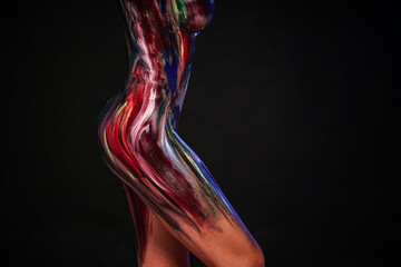 Body part art. Photo of female sensual creative body in colorful paints on a black studio...