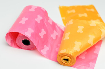 Colorful bag rolls for collecting dog excrement on white background. Orange and light purple with...