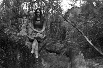 Young woman sitting on a big tree in black and white