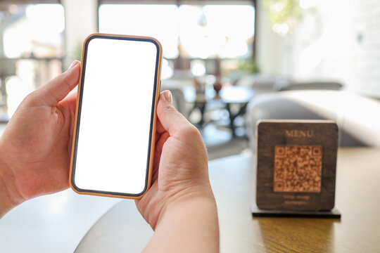 Mockup image of woman's hands holding white mobile phone with blank screen in cafe