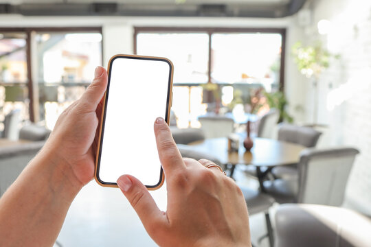 Mockup image of woman's hands holding white mobile phone with blank screen in cafe