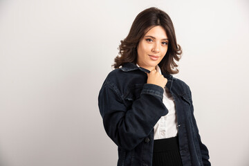 Positive woman in denim jacket standing on white background