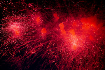 A bright firework with a red glowing center with red sparks and smoke flying towards the background...