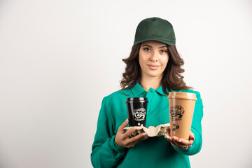 Female courier in green uniform holding coffee cups