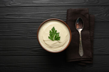 Cream of cauliflower soup on a dark wooden background.