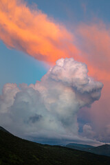 orange cirro-cumulus and cumulus clouds in the evening light at sunset in the mountains
