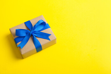 Wrapped christmas or other holiday handmade present in craft paper with colored ribbon. Present box, decoration of gift on table, top view with copy space