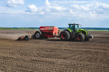 The tractor is sowing corn on a sunny spring day. Farmer's work in the field