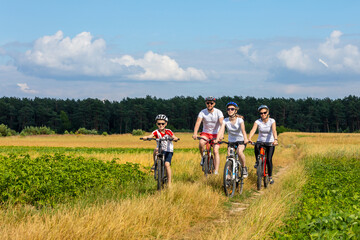 Fototapeta premium family of cyclists ride outdoors. Happy mother father and kids on bikes cycling outdoors.