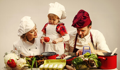 Mother and father teach little son cooking. Family with small child boy preparing food at kitchen.