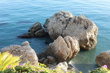 Hidden beach by the ocean sea with natural caves, sand and cliff