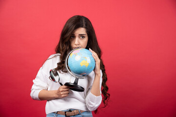 Smart woman posing with globe and magnifying glass