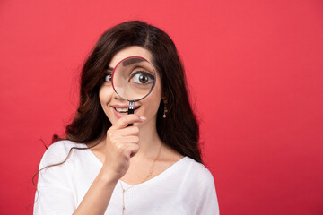 Young woman looking at camera with magnifying glass