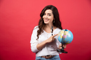 Surprised woman posing with globe and magnifying glass