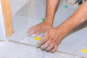 A plastic clip and wedge leveling system is used in the bathroom construction process applying tile adhesive floor