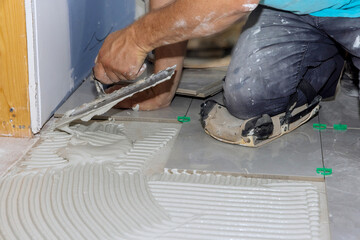 Bathroom renovation works with put adhesive on tiles, spread wet mortar first