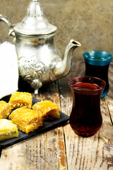 Pistachio baklava dessert with teapot on wood table. Traditional Turkish cuisine delicacies