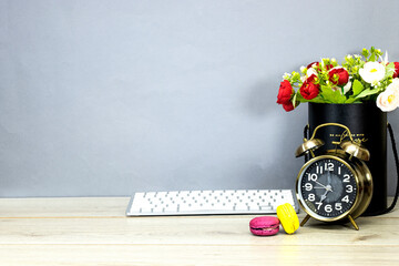 bouquet of flowers in black box and macaron cookies with alarm clock showing seven o'clock on wood...
