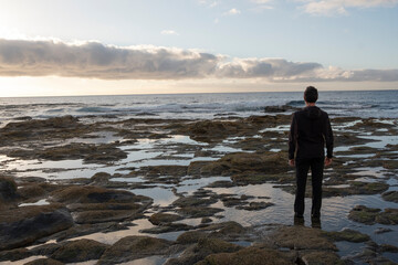 Man on the sea shore watching the sunrise.