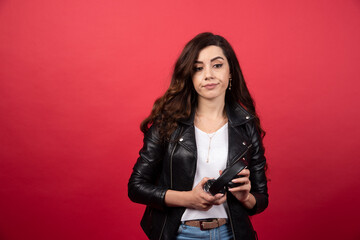 Young woman holding headphones and posing on a red background