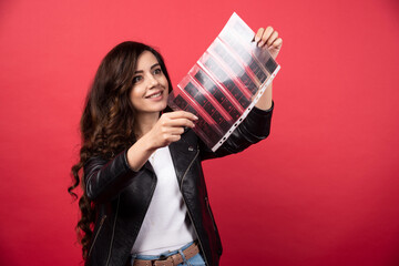 Young woman looking on a file with a photo tape on a red background