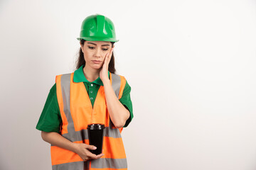Young female constructor holding black cup
