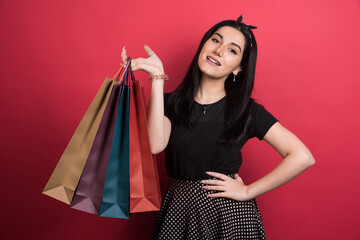 Woman showing her bags on red background