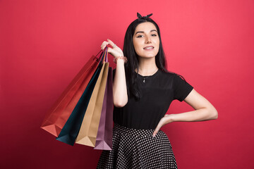 Woman holding her bags on red background