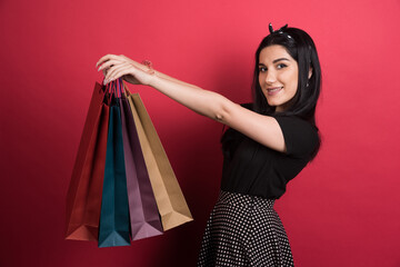 Woman holding her bags on red background