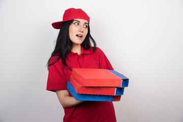 Young delivery woman holding a three boxes of pizza on white background