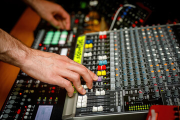 Hand of a sound engineer on sound console mixer. Equalizer control
