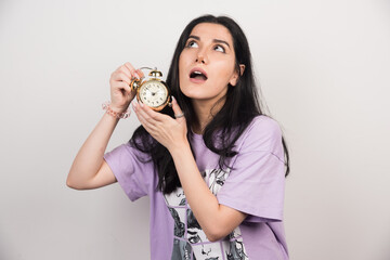 Young woman posing with clock on white background